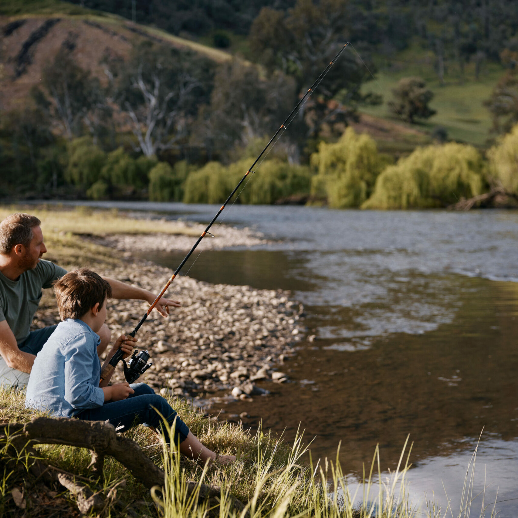 Boy and man fishing along the Murray River on the Great River Road, highlighting the abundant fishing spots and scenic beauty of the area.