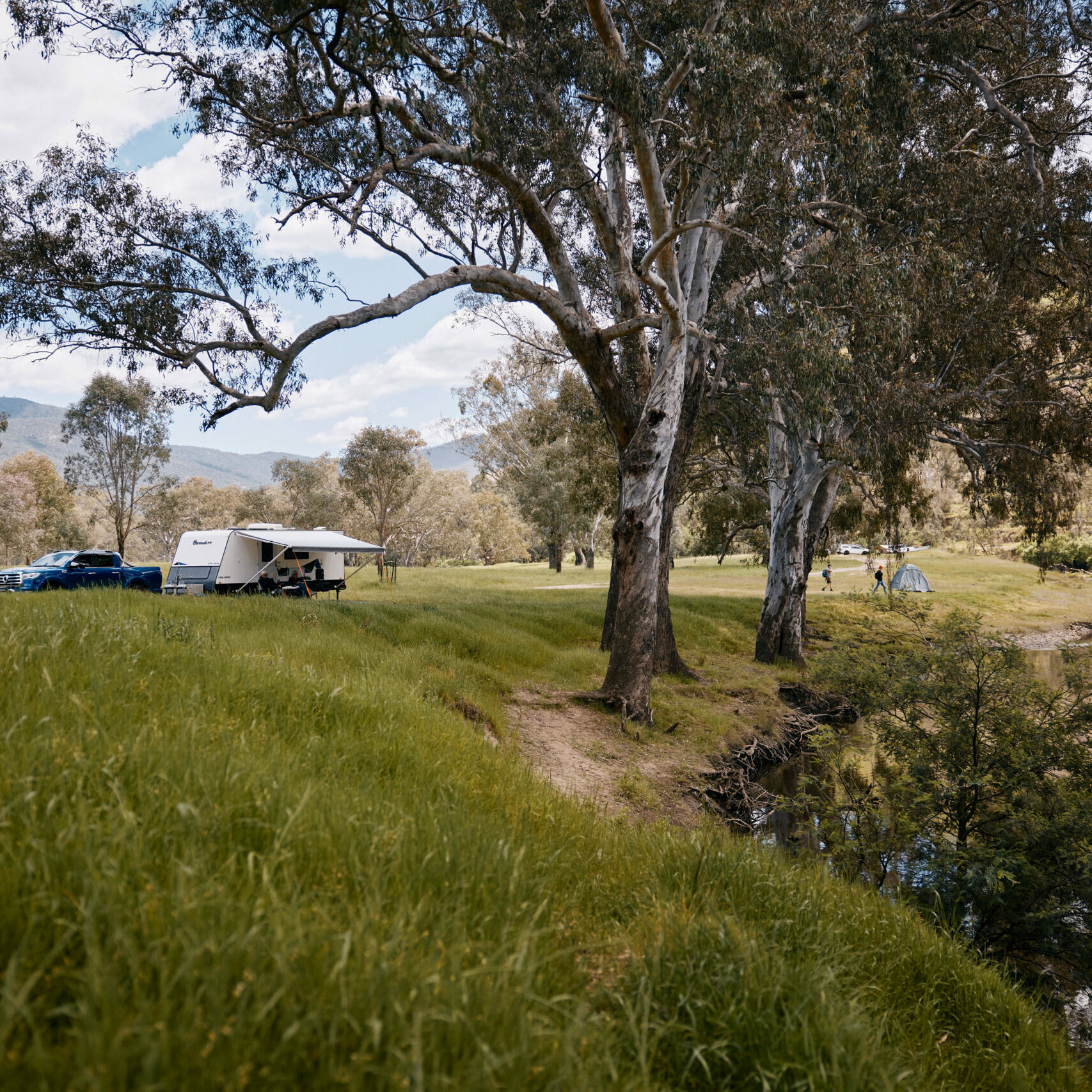 Caravan parked by a tranquil lake at a caravan park along the Great River Road, showcasing the ideal riverside camping experience in nature.